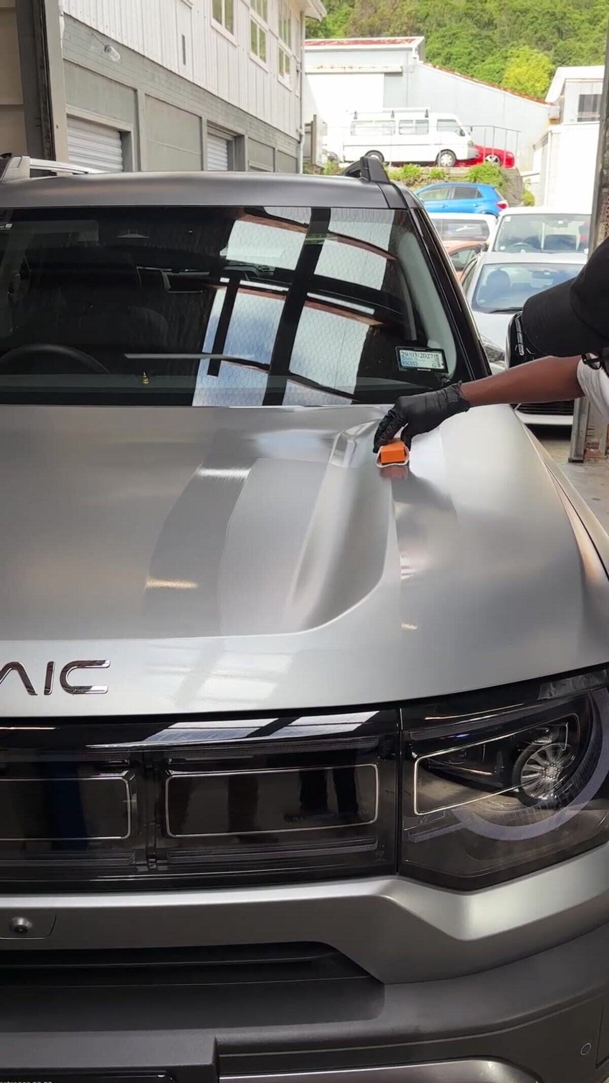 Ceramic coating being spread across a bonnet with an applicator block