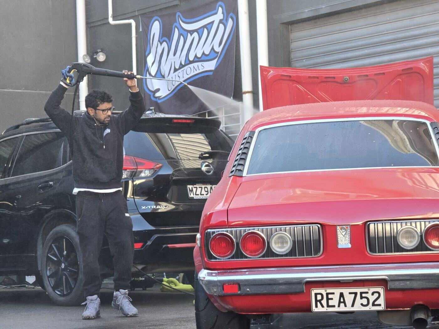 Pressure washing a classic coupe outside the Infinity Customs workshop in Taita