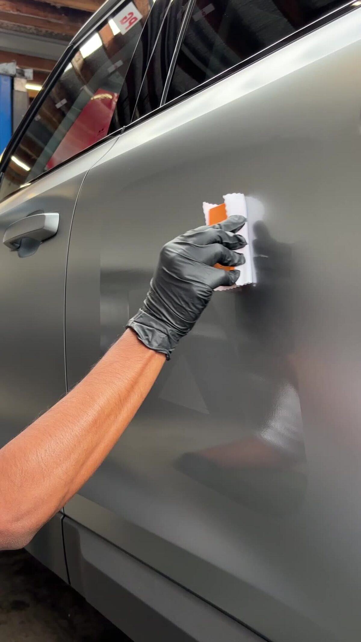 Graphene coating being applied panel by panel down the side of an SUV