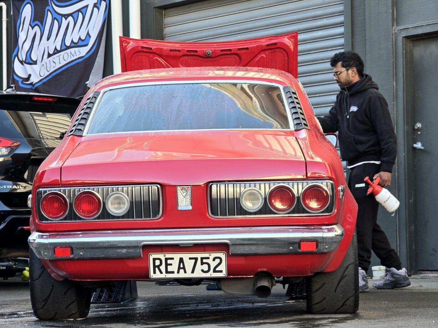 A red classic Mitsubishi coupe being detailed outside our Taita workshop